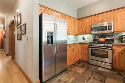 a stainless steel refrigerator in a kitchen with wooden cabinets at Cabins 13 in Old Mammoth