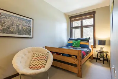 a bedroom with a bed and a chair and a window at Solstice 21 in Mammoth Lakes