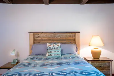 a bedroom with a bed with a wooden headboard and a lamp at North Shore - Cozy Cabin in Wood Vista