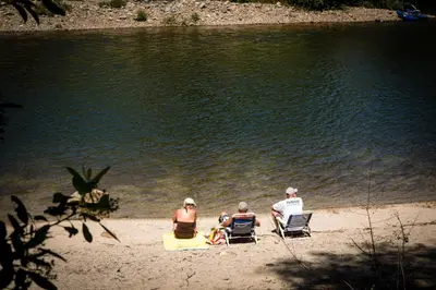 three people sitting in lawn chairs on the beach at Ponderosa Camping Resort One-Bedroom Cabin 2 in Lotus