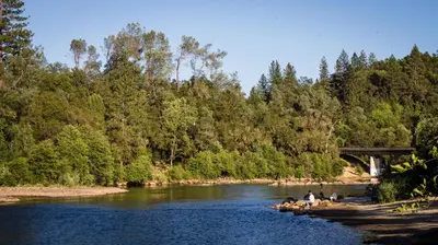 a group of people on rocks in a river with a bridge at Ponderosa Camping Resort One-Bedroom Cabin 2 in Lotus