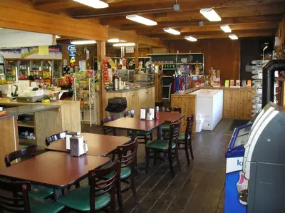 a restaurant with tables and chairs and a kitchen at Ponderosa Camping Resort One-Bedroom Cabin 2 in Lotus