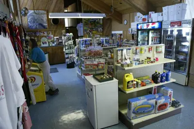 a store with a woman sitting at a counter in a store at Snowflower Camping Resort Cabin 4 in Emigrant Gap