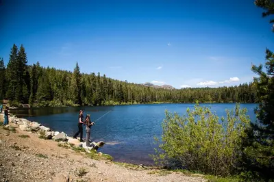 a man and a woman and a dog standing next to a lake at Snowflower Camping Resort 16 ft. Yurt 10 in Emigrant Gap