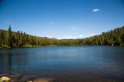 a large blue lake with trees in the background at Snowflower Camping Resort 16 ft. Yurt 10 in Emigrant Gap