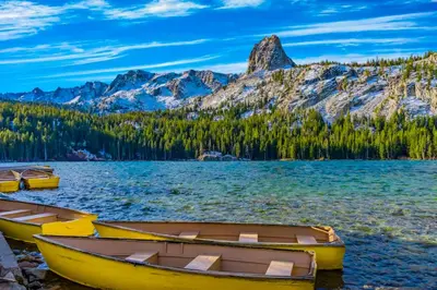 three boats on the shore of a lake with mountains at Helios North in Mammoth Lakes