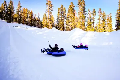 a group of three people riding on a snowboard in the snow at Helios North in Mammoth Lakes
