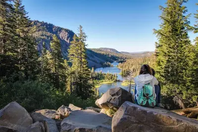 a woman sitting on a rock overlooking a lake at The Lodges 1145 in Mammoth Lakes