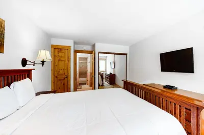 a bedroom with a large white bed and a flat screen tv at The Summit 67 in Old Mammoth