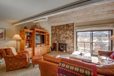 a living room with couches and a stone fireplace at Snowcreek 233 in Mammoth Lakes