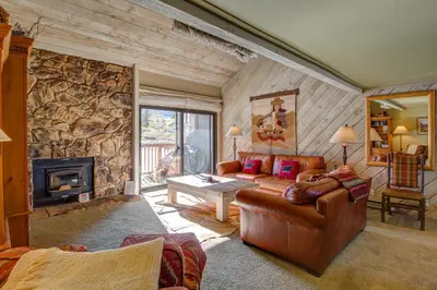 a living room with a couch and a stone wall at Snowcreek 233 in Mammoth Lakes