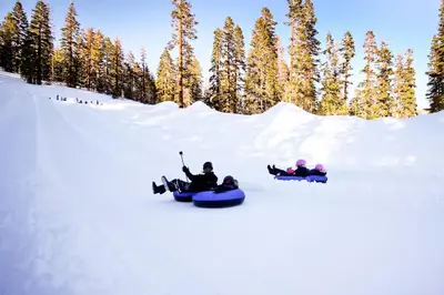 three people are riding down a snow covered slope on snowboards at Timberline 35 in Mammoth Lakes
