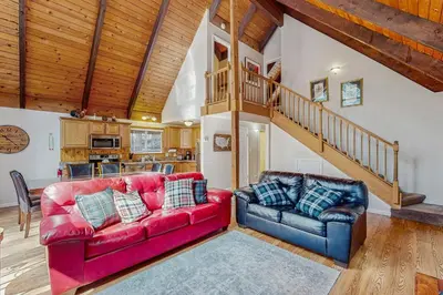a living room with a red couch and a staircase at Charming Tahoe Chalet in Tahoe Valley