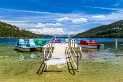 a chair on the shore of a lake with boats at Donner Lakefront Retreat in Truckee