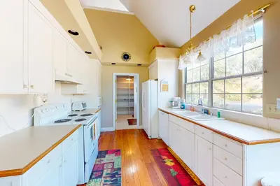 a kitchen with white cabinets and a large window at Great Escape Cabin (08/253) in Groveland