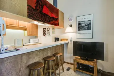 a living room with a bar with stools and a tv at Northstar Ski Trails in Truckee