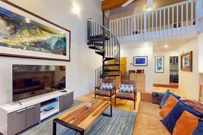 a living room with a large television and a staircase at Squaw Valley Ski Flat in Olympic Valley