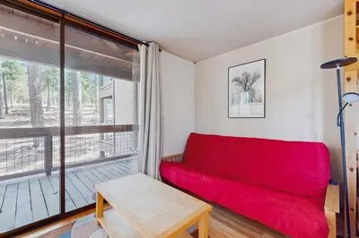 a red couch in a room with a large window at Aspen Grove Studio at Northstar in Truckee
