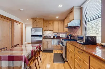 a kitchen with wooden cabinets and a table with a table cloth at Aspen Grove Studio at Northstar in Truckee