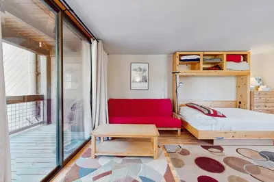 a bedroom with a bed and a red couch at Aspen Grove Studio at Northstar in Truckee
