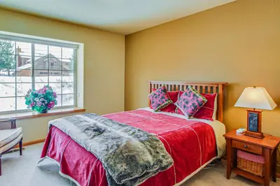 a bedroom with a bed with a red blanket and a window at Hillside View Vacation Home in Truckee