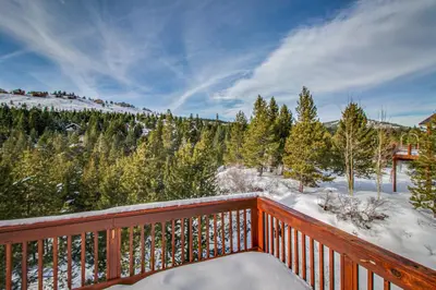a wooden balcony with snow on the trees at Hillside View Vacation Home in Truckee