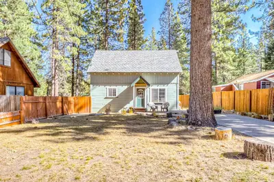 a small white house with a fence and a tree at Foxglove Terrace in South Lake Tahoe