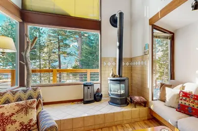a living room with a wood burning stove and windows at Squaw Valley Views Condo #15 in Olympic Valley