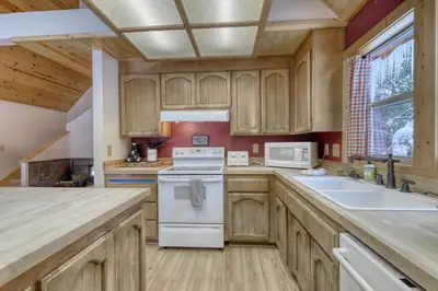 a kitchen with wooden cabinets and a white stove top oven at Snowpeak Chalet in Tahoe Donner in Truckee