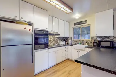 a kitchen with white cabinets and a stainless steel refrigerator at West Shore Lakeview Beauty* in Homewood