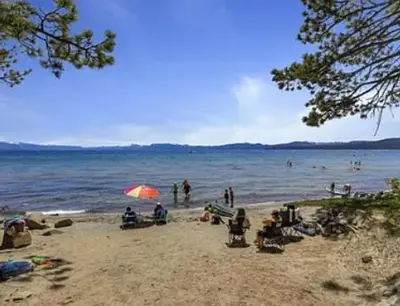a group of people on a beach with an umbrella at Streamside Townhome in Kings Beach
