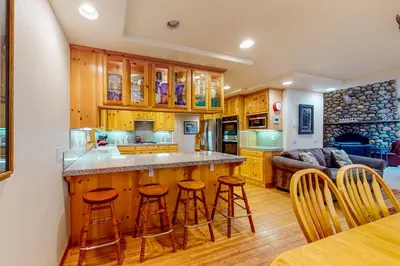 a kitchen with wooden cabinets and bar stools at Snowpeak Tahoe Donner Golf Course Views in Truckee