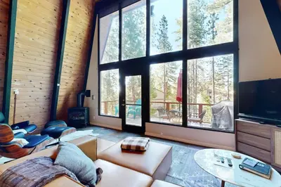 a living room with a couch and a large window at Canterbury Kings Beach Treehouse in Kings Beach