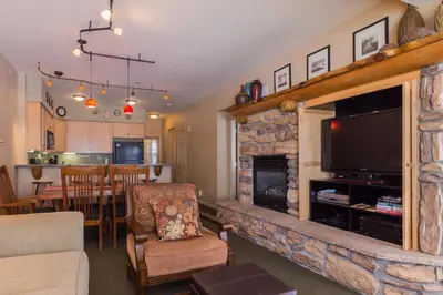 a living room with a stone fireplace with a flat screen tv at Mammoth Green # 105 in Mammoth Lakes