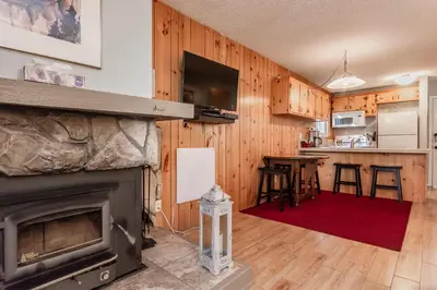 a living room with a fireplace and a kitchen at Mammoth View Villas # 34 in Mammoth Lakes