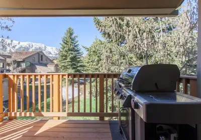 a grill on a deck with a view of a house at Snowcreek # 320 - Phase II in Mammoth Lakes