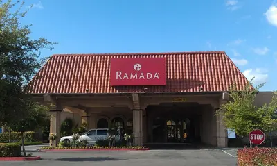 a building with a red sign that reads ramada at Ramada by Wyndham Fresno North in Fresno