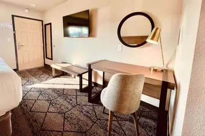 a room with a desk with a mirror and a chair at Ramada by Wyndham Modesto Yosemite Area in Modesto