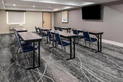 a conference room with tables and chairs and a screen at Ramada by Wyndham Modesto Yosemite Area in Modesto