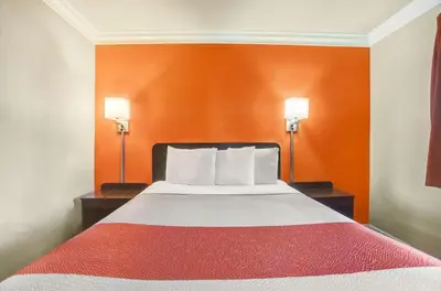 a bed in a hotel room with orange walls at Motel 6-Fresno, CA - Belmont Ave in Fresno