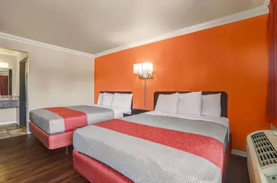 a hotel room with two beds and an orange wall at Motel 6-Fresno, CA - Belmont Ave in Fresno