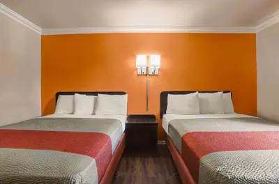 two beds in a room with orange walls at Motel 6-Fresno, CA - Belmont Ave in Fresno