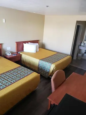 a hotel room with two beds and a table at University Inn Fresno in Fresno