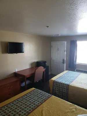 a hotel room with two beds and a desk at University Inn Fresno in Fresno