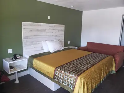 a bedroom with a bed and a red chair at University Inn Fresno in Fresno