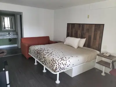 a bedroom with a bed and a red chair at University Inn Fresno in Fresno