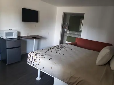 a small room with a bed and a microwave at University Inn Fresno in Fresno