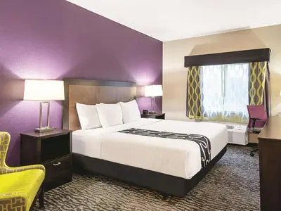 a hotel room with a large bed and a yellow chair at La Quinta Inn by Wyndham Livermore in Livermore