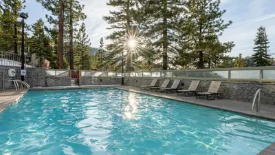 a swimming pool with chairs and trees in the background at Holiday Inn Club Vacations - Tahoe Ridge Resort in Stateline