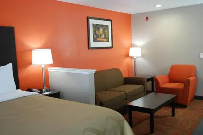a hotel room with a bed and a couch and a chair at Quality Inn & Suites Fresno Northwest in Fresno